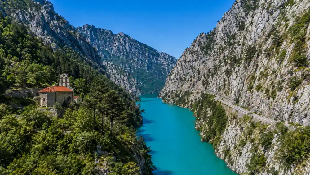 Tyrkysové Pivské jezero mezi strmými vápencovými stěnami u Plužine