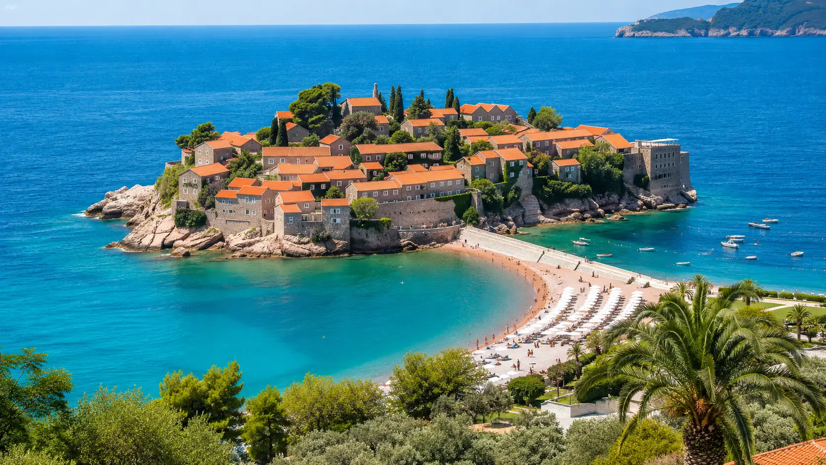 Ostrůvek Sveti Stefan s kamennými domky a pláží na Budvanské riviéře